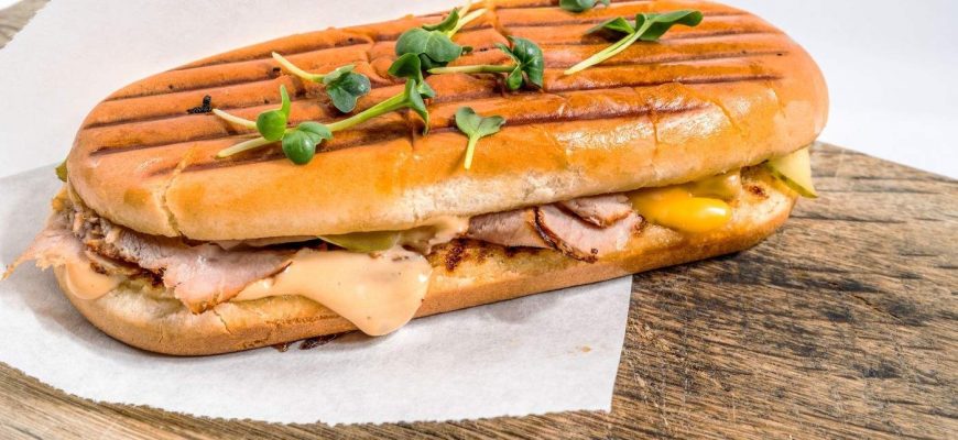 Sandwich la grătar servit pe o placă de lemn